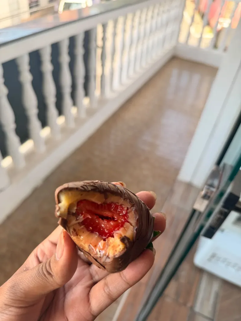 Doce com cobertura de chocolate e recheio de morango